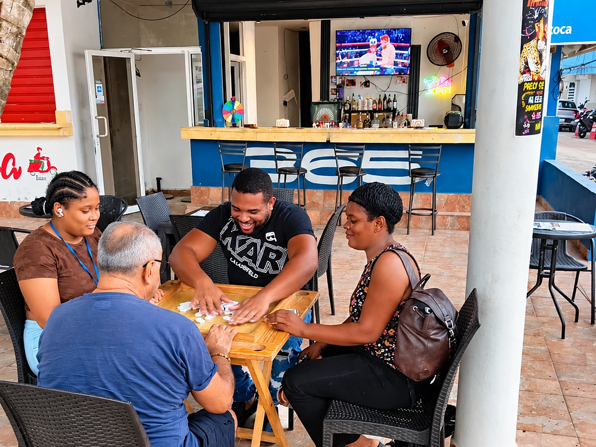 Four friends playing dominoes on a wooden table on the 365 Beach Bar patio